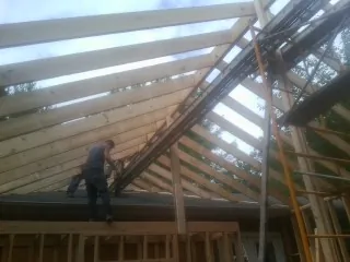 Rafters going up over a new addition with a worker on the wall in Vergennes