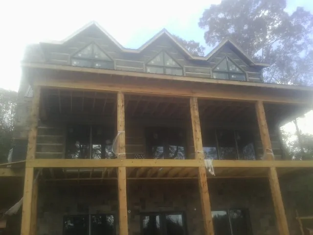 Dormers and porch framing on a large log home under construction — Roof Coating work by our crew in Vergennes