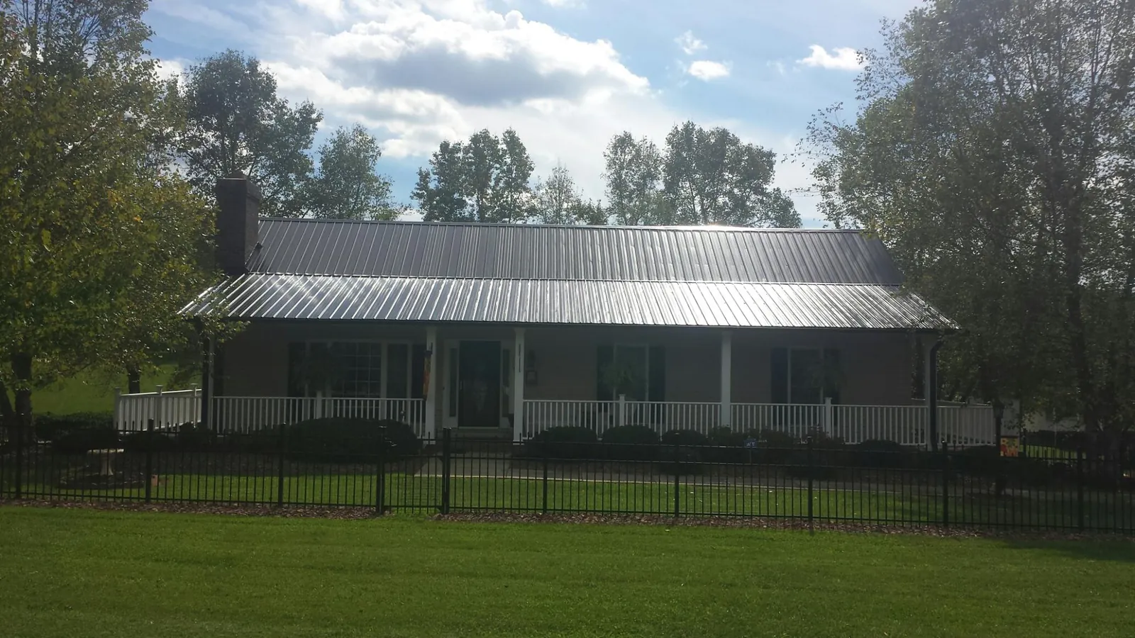 Gray metal roof on a brick ranch with a full width front porch — Gutter Guard Installation work by our crew in Vergennes