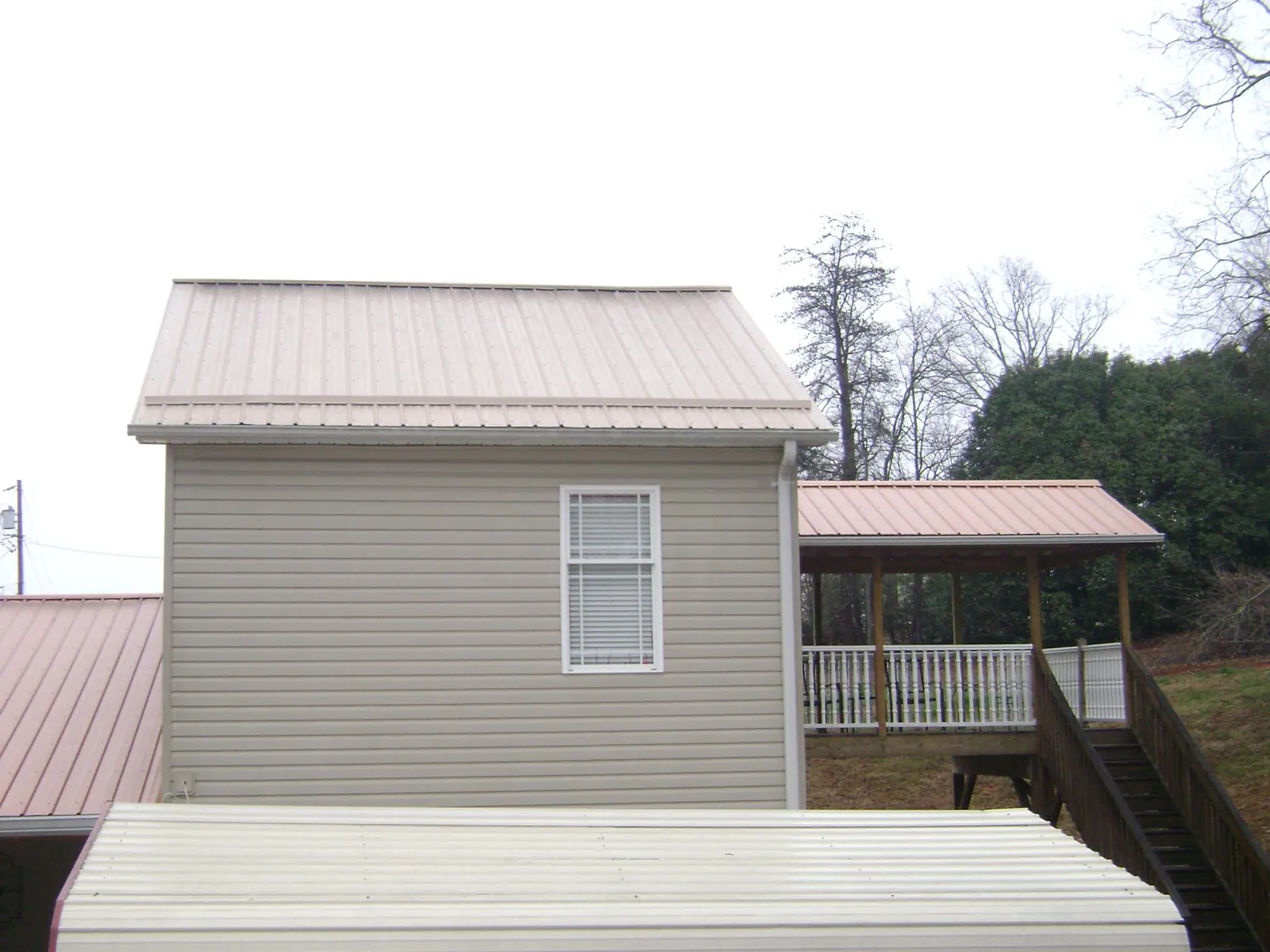 Tan metal roofs on a two story addition and attached porch, from a Roof Replacement job in Vergennes