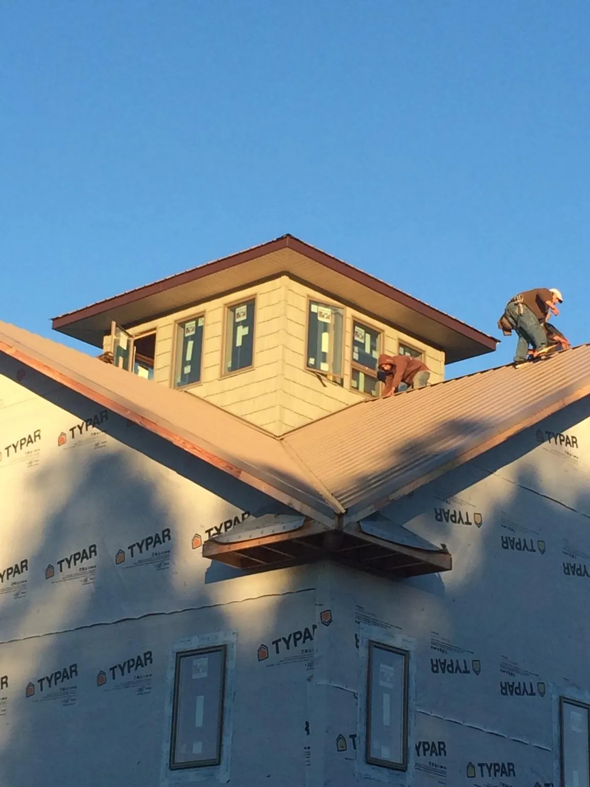 Roofers working around a rooftop cupola on a new metal roof at sunset — Roof Waterproofing in Vergennes by Roofing Brothers